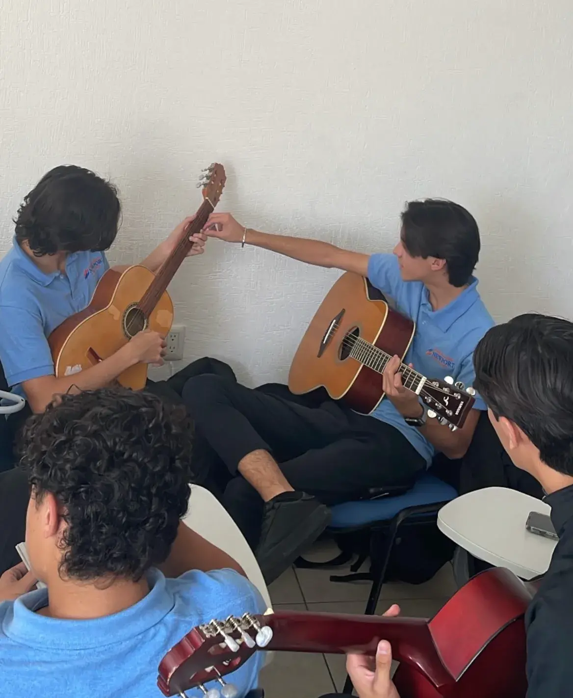 Grupo de jóvenes sentados en interiores tocando y afinando guitarras acústicas